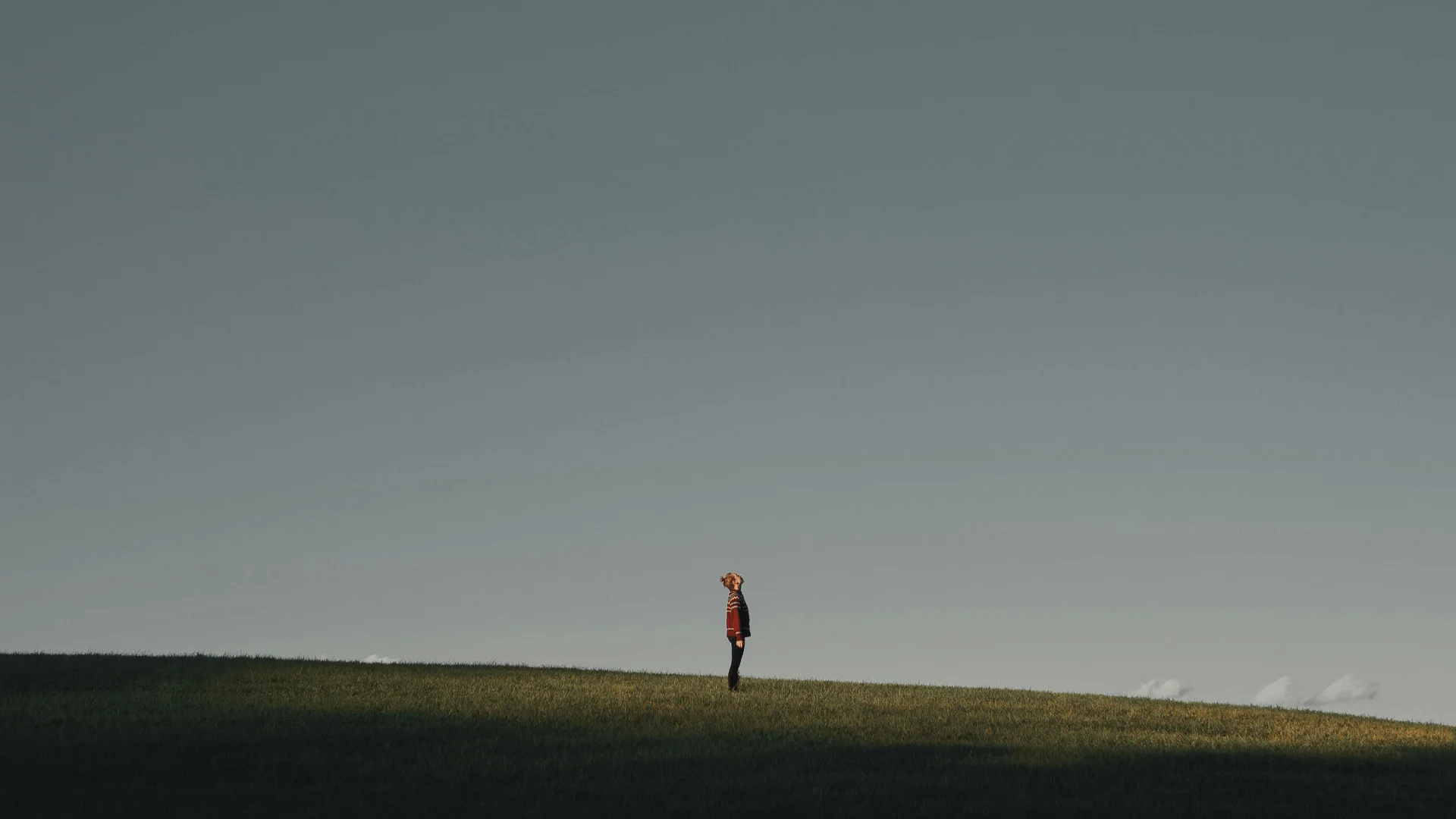 Eine weite Landschaft mit offenem Himmel und einem Mann mit roter Jacke, der staunend in den Himmel schaut.